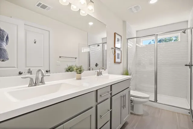 a bathroom with a double vanity sink toilet and shower