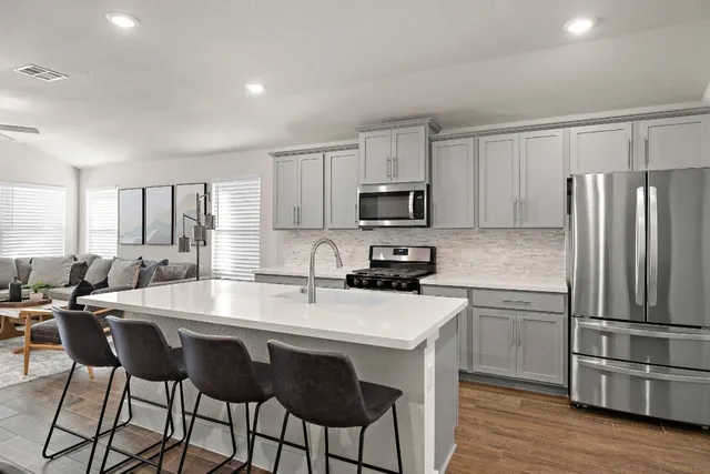 a kitchen with kitchen island granite countertop a table chairs microwave and refrigerator