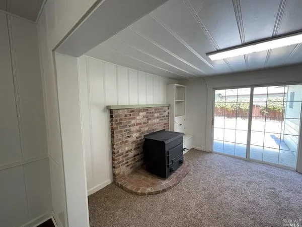 a view of an empty room with a fireplace and a window