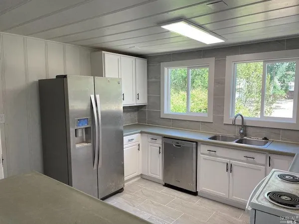 a kitchen with stainless steel appliances granite countertop a refrigerator sink and window