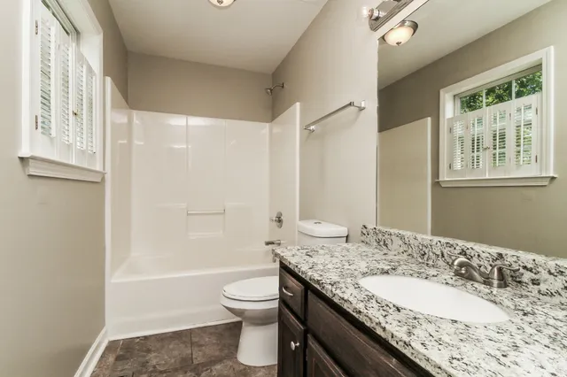 a bathroom with a granite countertop sink toilet and shower