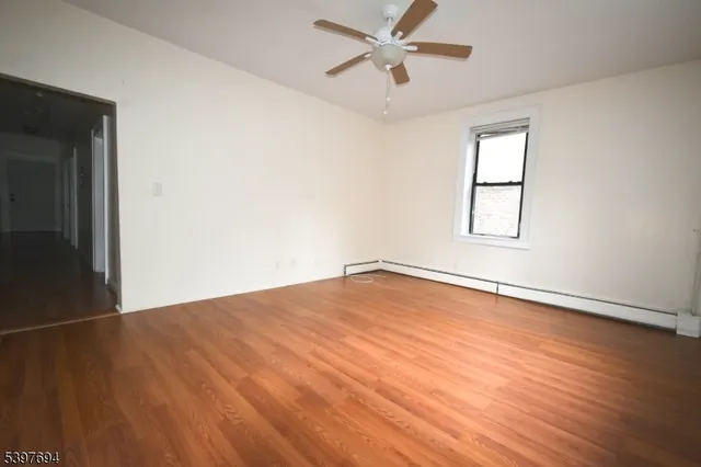 an empty room with wooden floor fan and windows