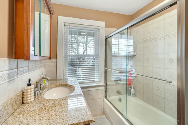 a bathroom with a granite countertop sink and a bathtub