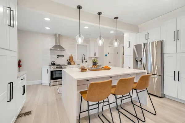 a kitchen with stainless steel appliances kitchen island refrigerator stove and white cabinets