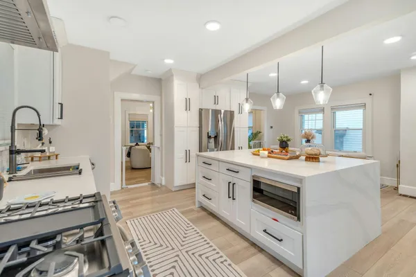 a kitchen with kitchen island a stove a sink dishwasher and white cabinets with wooden floor