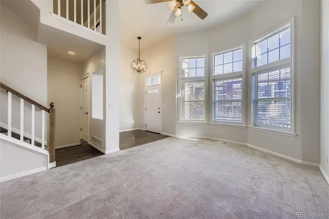 an empty room with windows and chandelier fan