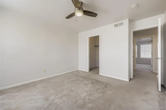 an empty room with a ceiling fan and carpet