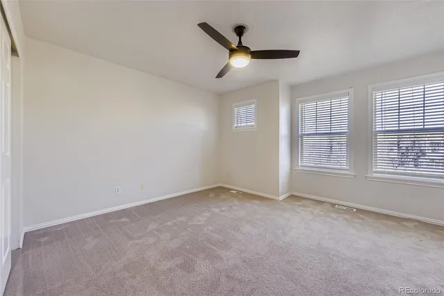 an empty room with a ceiling fan and windows