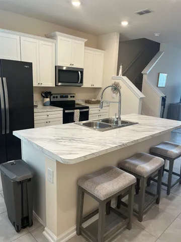 a kitchen with stainless steel appliances kitchen island granite countertop a table chairs and a refrigerator
