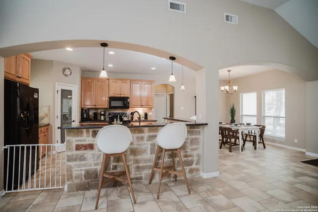 a dining room with furniture a chandelier and kitchen view