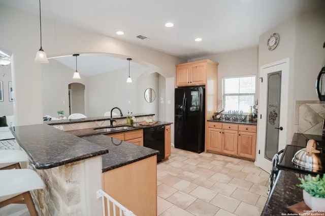 a large kitchen with granite countertop a sink and a refrigerator