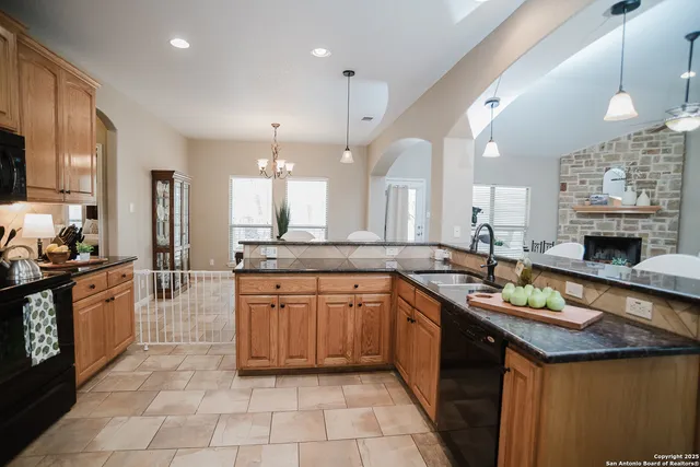 a large kitchen with a large counter top space a sink stainless steel appliances and cabinets