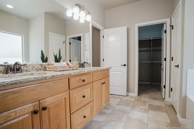 a bathroom with a granite countertop sink mirror and cabinets