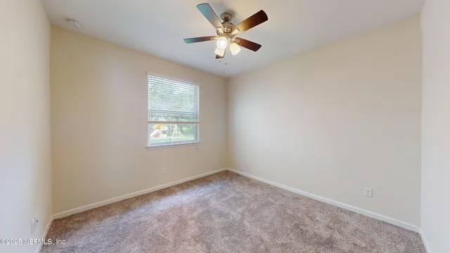 an empty room with windows and ceiling fan