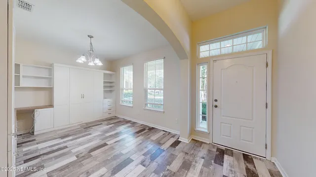 a view of an empty room with window and wooden floor