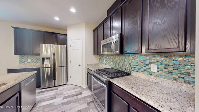 a kitchen with stainless steel appliances granite countertop a sink stove and refrigerator