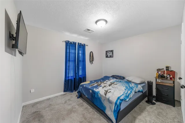 a bedroom with a bed and flat tv screen on the dresser