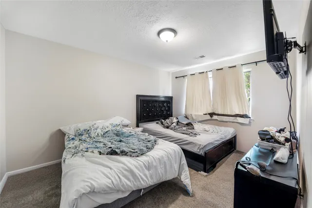 a bedroom with bed a mirror and a window