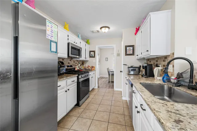 a kitchen with granite countertop a sink stainless steel appliances and cabinets