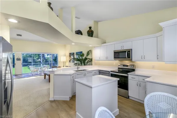 a kitchen with stainless steel appliances a stove a sink a microwave a center island and furniture