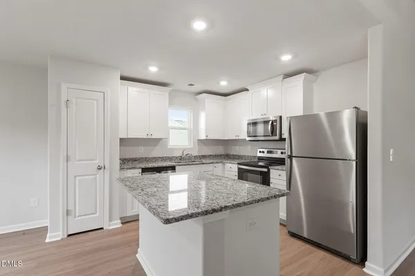 a kitchen with kitchen island granite countertop stainless steel appliances refrigerator and microwave