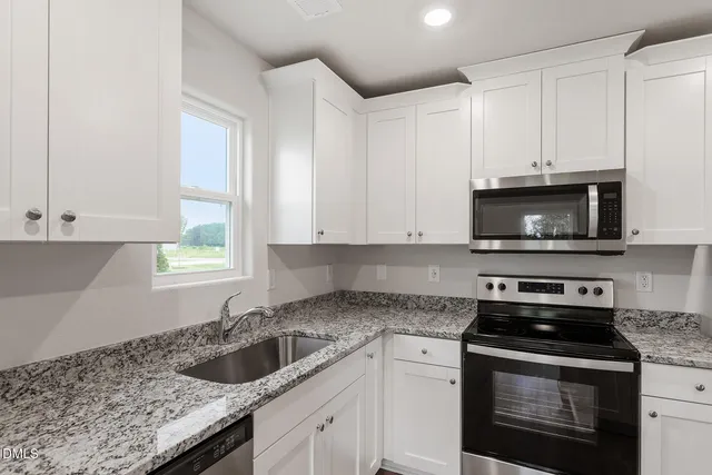 a kitchen with granite countertop white cabinets and a stove