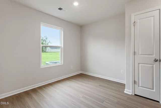 an empty room with wooden floor and window