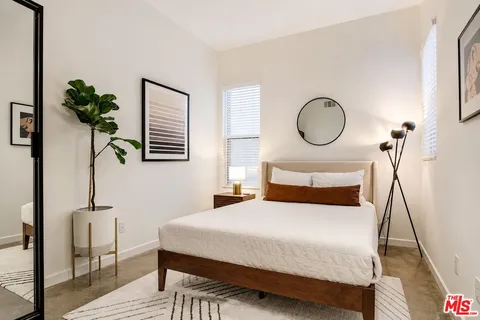 a bedroom with a bed a potted plant and a dresser
