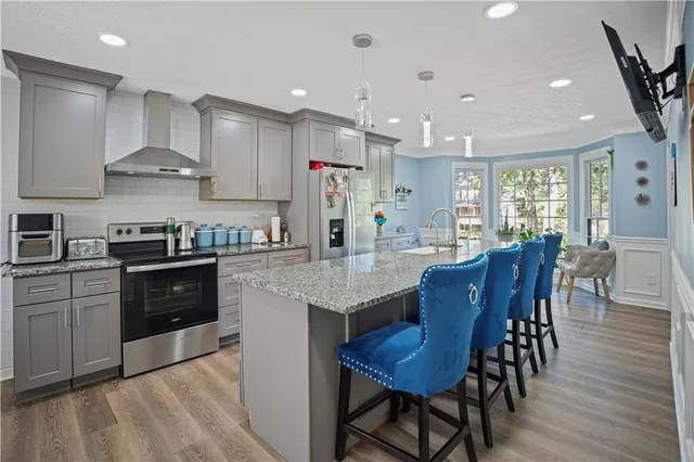 a kitchen with stainless steel appliances granite countertop a stove a refrigerator a kitchen island a dining table and chairs