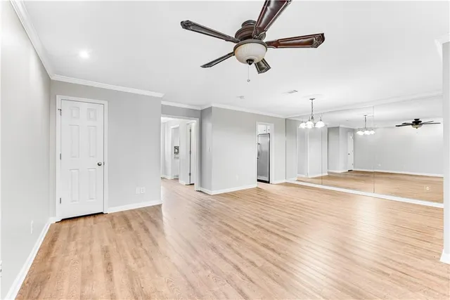 an empty room with wooden floor fan and windows