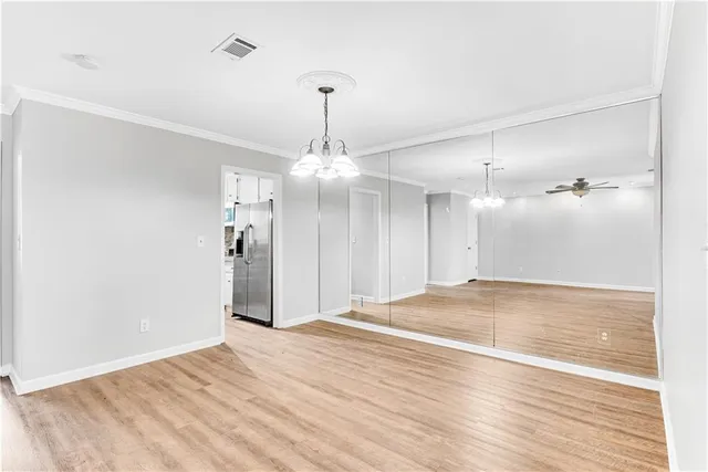 a view of an empty room with wooden floor and a ceiling fan