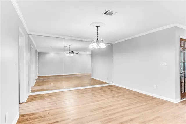 an empty room with wooden floor ceiling fan and window