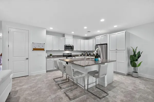 a kitchen with white cabinets and refrigerator