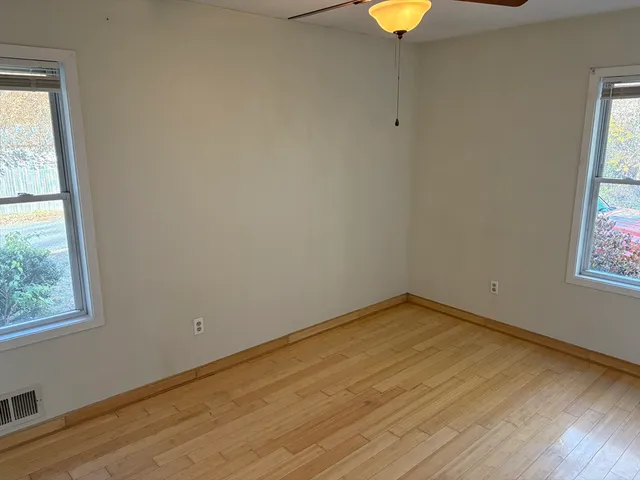 a view of an empty room with a window and wooden floor