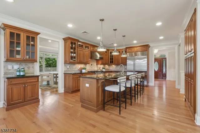 a kitchen with stainless steel appliances kitchen island granite countertop a refrigerator a stove a sink a dining table and chairs with wooden floor