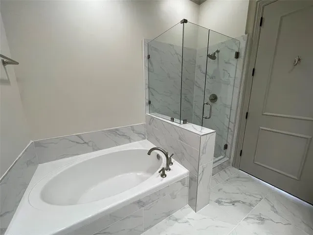 a spacious bathroom with a tub sink shower and mirror