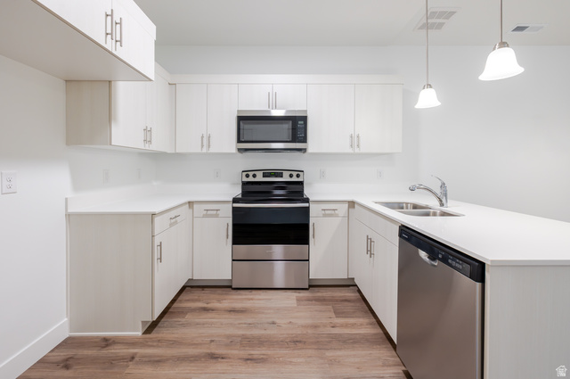 4661 Poplar Way, Unit R301 Mapleton, UT 84664 - Photo 11 of 17 Kitchen featuring stainless steel appliances, a peninsula, light wood-type flooring, and pendant lighting
