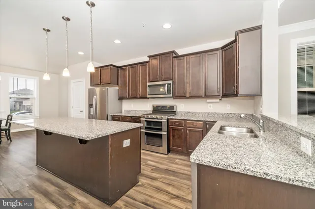 a kitchen with stainless steel appliances granite countertop a kitchen island hardwood floor sink stove and granite counter top