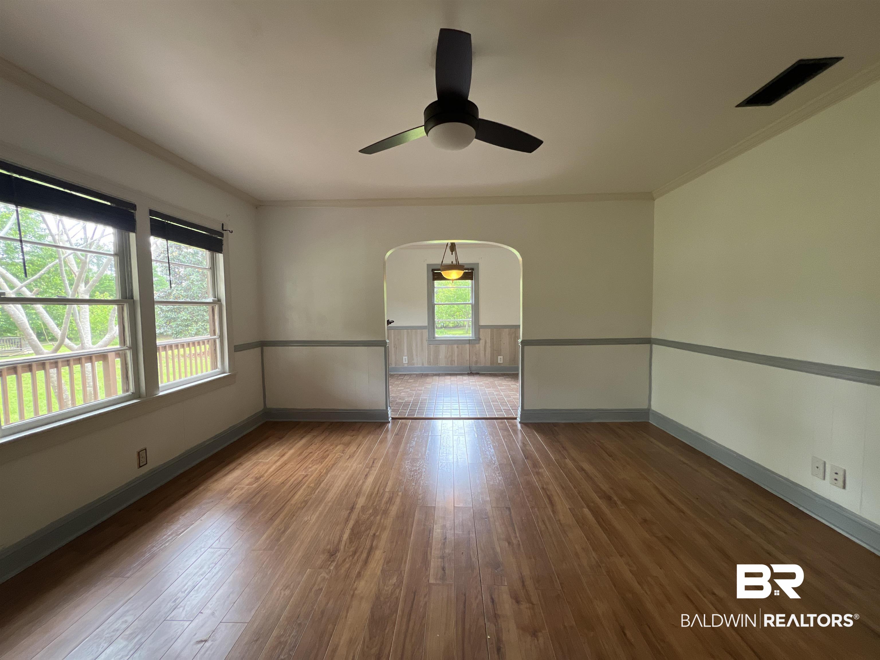 13301 A Hugh Fort Road Grand Bay, AL 36541 - Photo 5 of 34 Unfurnished room with arched walkways, baseboards, hardwood / wood-style flooring, crown molding, and a ceiling fan