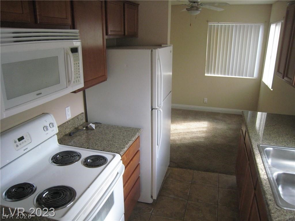 1844 North Decatur Boulevard, Unit 204 Las Vegas, NV 89108 - Photo 4 of 8 Functional kitchen with ample cabinet space, flowing into a comfortable living area.