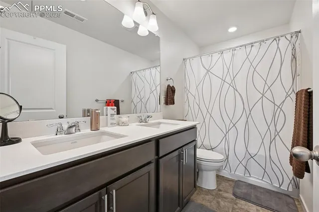 a bathroom with a double vanity sink toilet and a mirror