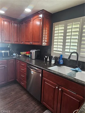 a kitchen with stainless steel appliances granite countertop wooden cabinets a sink and dishwasher with wooden floor