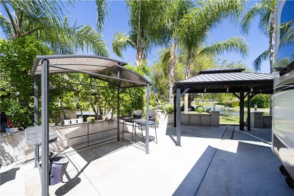 a view of a patio with table and chairs under an umbrella with a barbeque