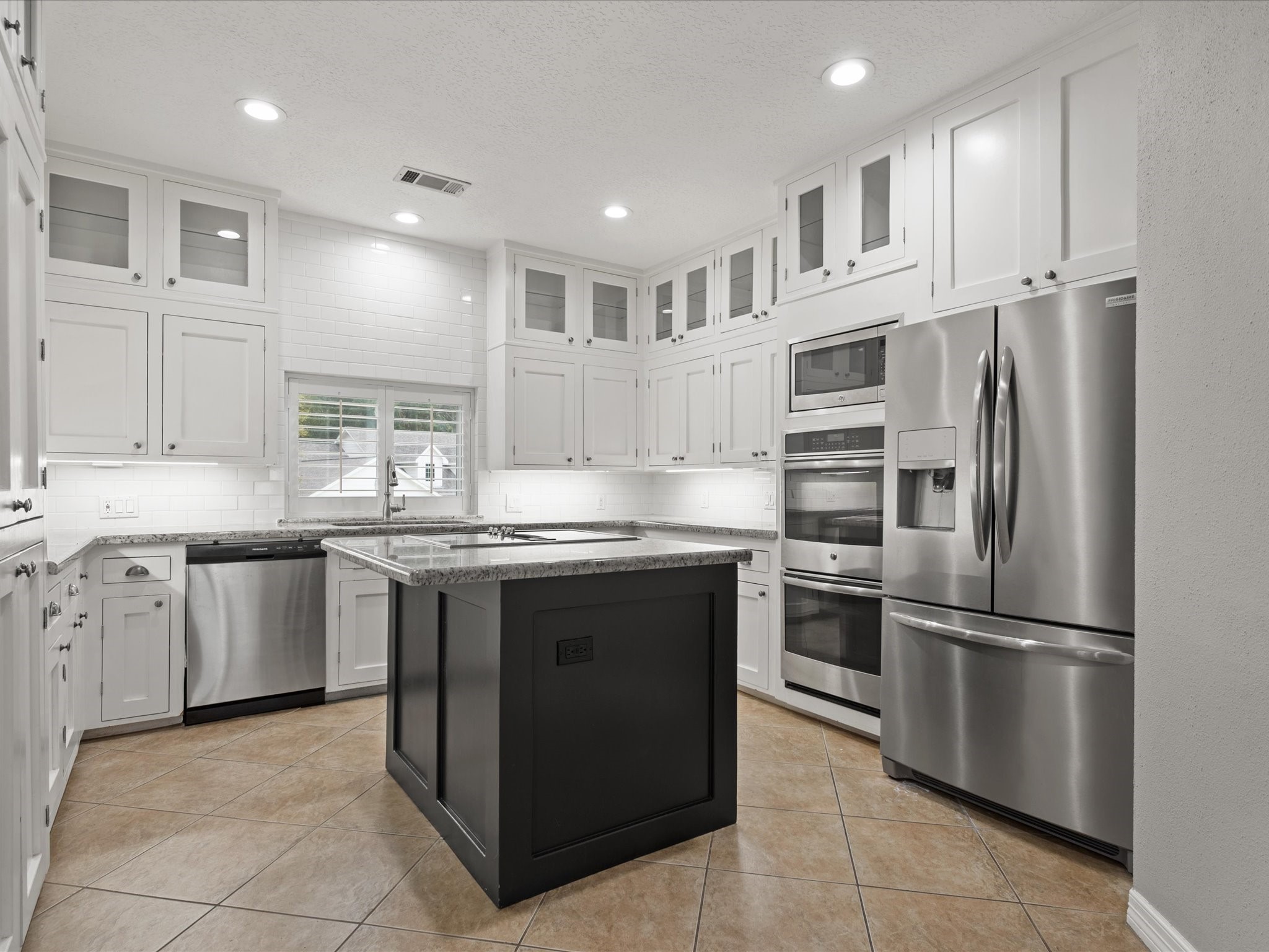 2906 Penninsula Point Montgomery, TX 77356 - Photo 11 of 48 The chef’s kitchen is a true
showstopper, featuring crisp
white cabinetry with glass-front
accents, stainless steel
appliances, and a center island
w/ cooktop!