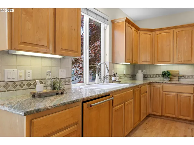 a kitchen with stainless steel appliances granite countertop a sink dishwasher cabinets and granite countertops with wooden floor
