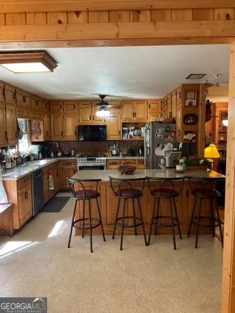 a kitchen with stainless steel appliances kitchen island granite countertop a table chairs sink and cabinets