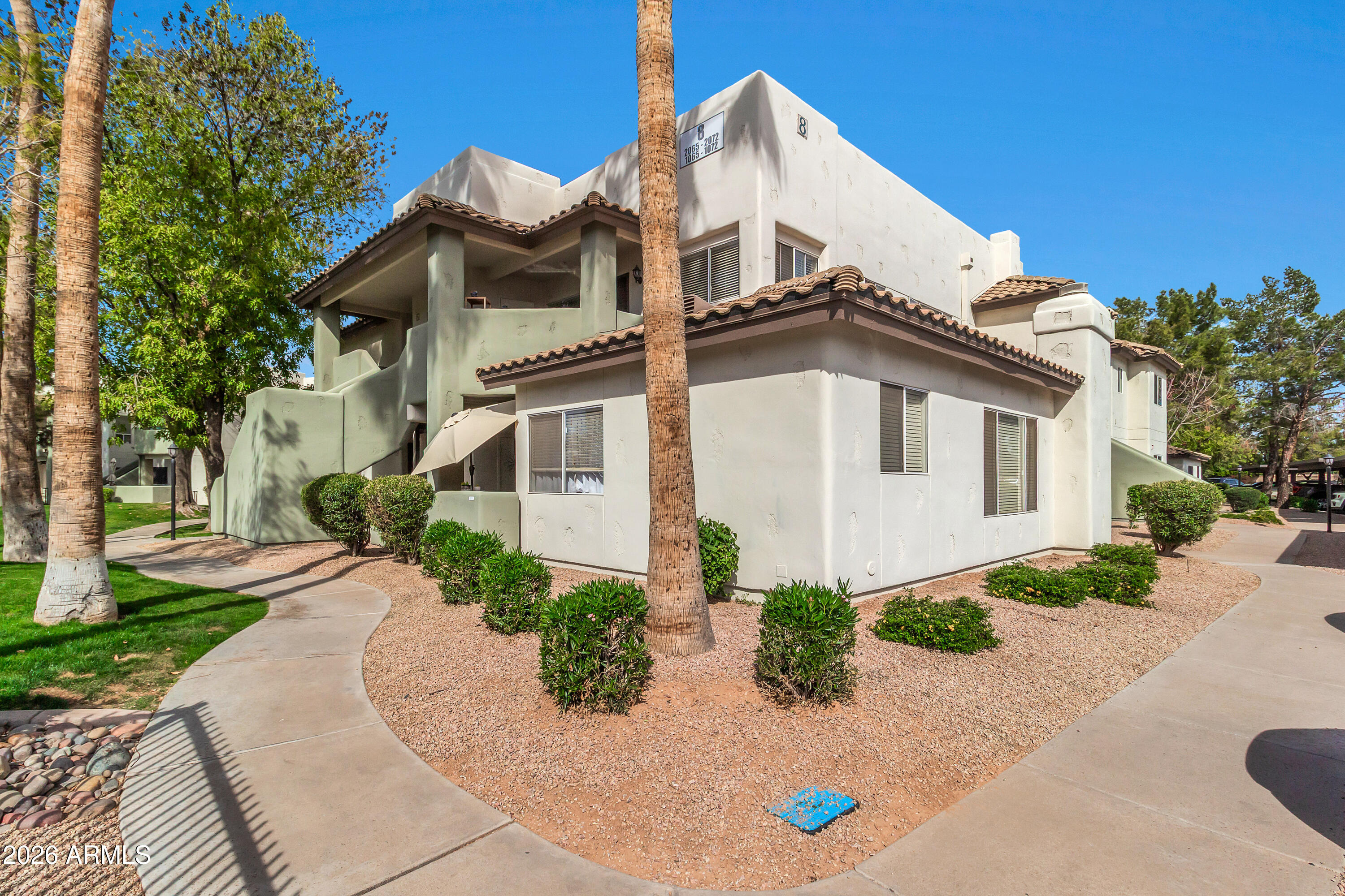 1825 West Ray Road, Unit 2072 Chandler, AZ 85224 - Photo 43 of 47 a view of a white house with a small yard and large tree and plants