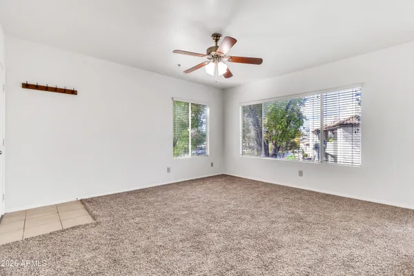 an empty room with chandelier fan and windows