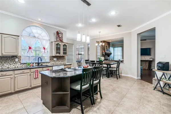 a dining hall with stainless steel appliances kitchen island granite countertop a table and chairs in it