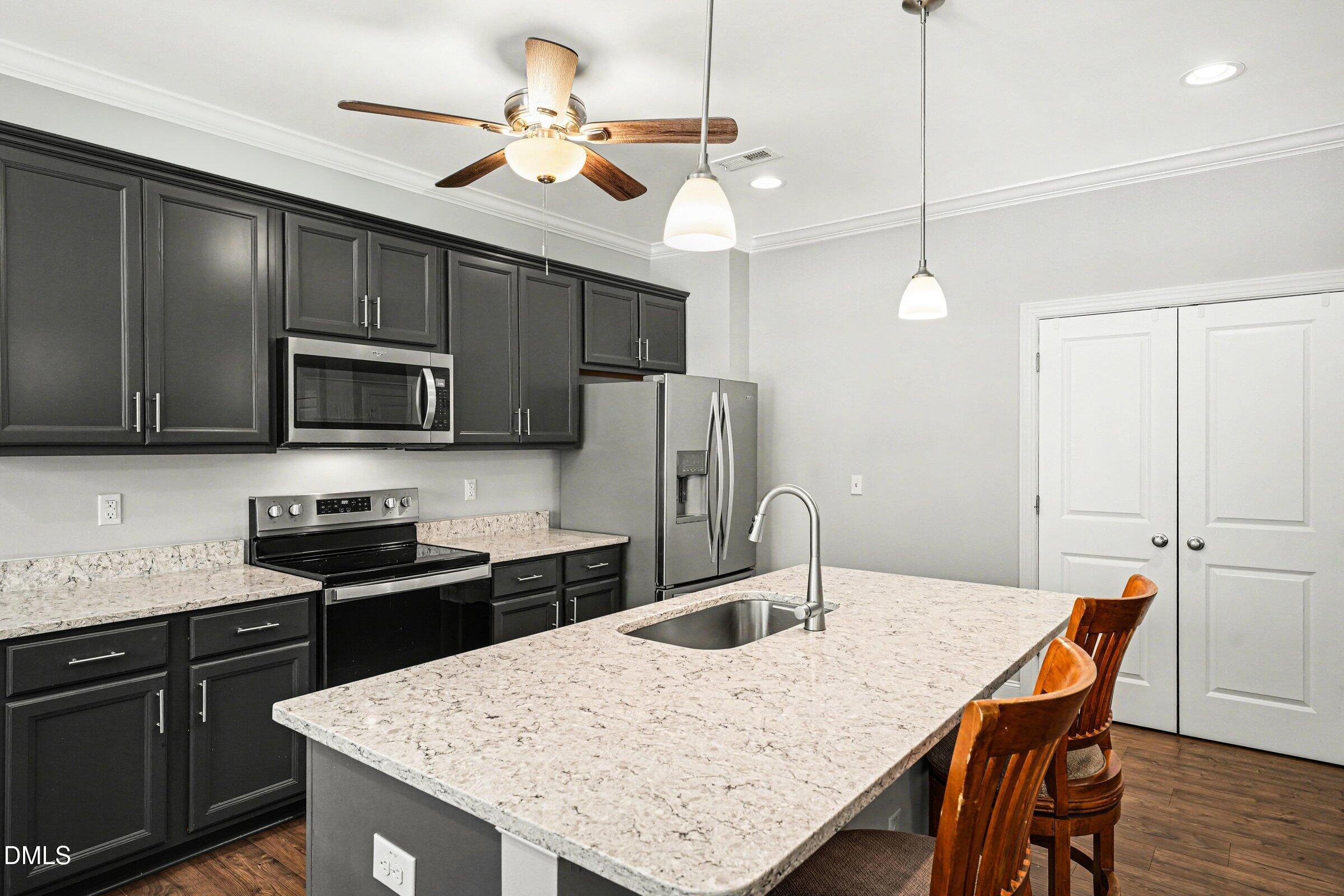 130 Aylebury Ridge Zebulon, NC 27597 - Photo 12 of 41 a kitchen with stainless steel appliances kitchen island granite countertop a kitchen island a stove a sink a refrigerator with a dining table and chairs